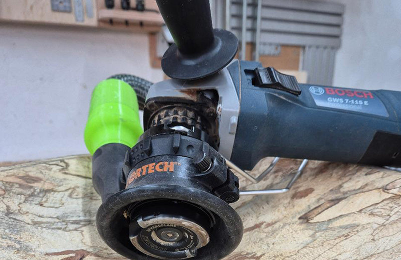 An Arbortech TURBOPlane blade fitted to a Bosch angle grinder, resting on a spalted timber surface